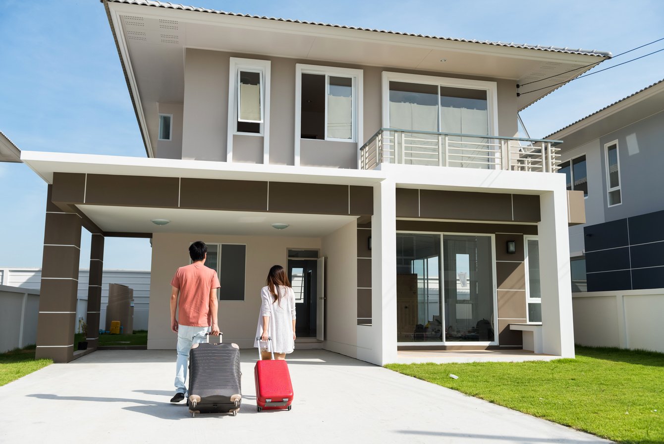 couple pull suitcases to move to new house