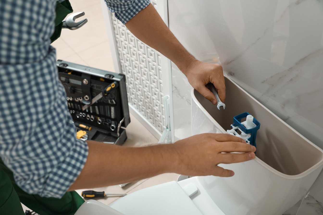 Professional Plumber Repairing Toilet in Bathroom, Closeup